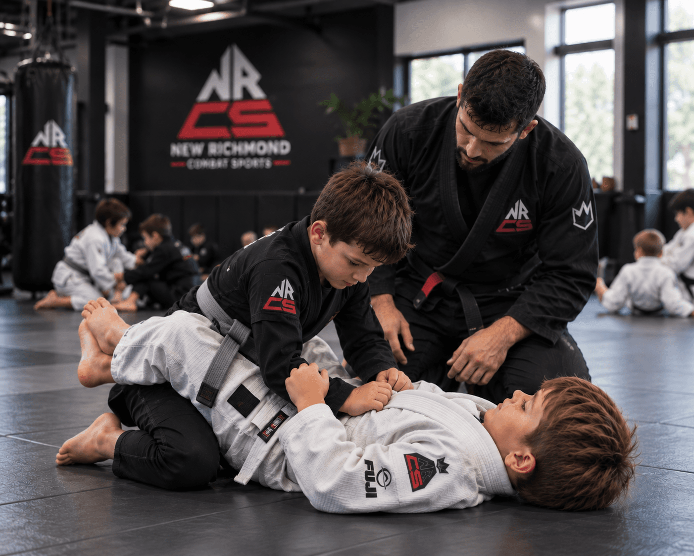 Kids training Brazilian jiu-jitsu with a coach on the mats
